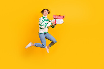 Full body photo of nice young girlfriend jumping with presents boxes happy birthday holiday isolated on bright yellow color background