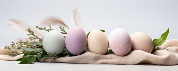 Composition with beautiful pastel colored Easter eggs, spring plant leaves and cloth on grey...