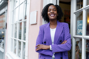 Portrait of female business owner standing in front of open store - obrazy, fototapety, plakaty