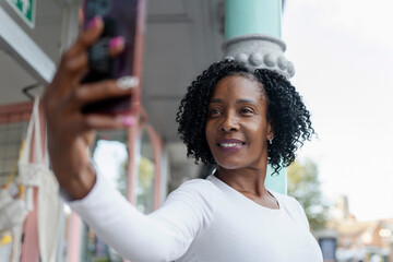 Smiling woman taking selfie in front of building