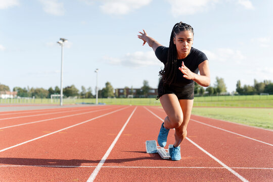 Female athlete sprinting off starting line at stadium