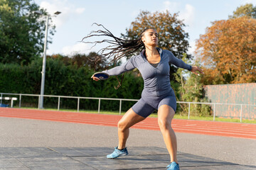 Female athlete training discus throwing at stadium