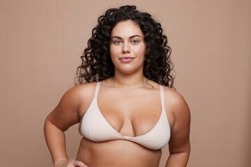 Studio portrait of young woman with curly hair wearing bra - obrazy, fototapety, plakaty