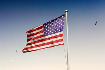 United States flag fluttering in the wind on sky.