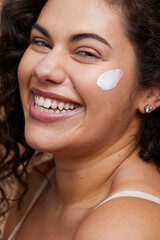 Close-up portrait of young woman applying face cream