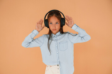 In headphones, positive energy. Cute young girl is in the studio against background