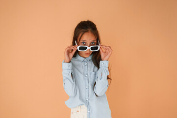 Funny facial expression and emotions. In sunglasses. Cute young girl is in the studio against...