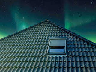 Open roof window in velux style with black roof tiles.