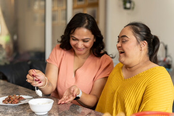 Mother eating dinner with down syndrome daughter at home