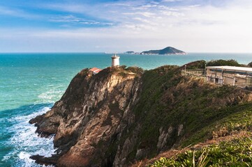 Lighthouse on the edge of a cliff with the sea on the background