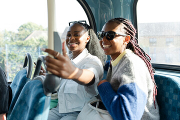 Young female friends riding city bus
