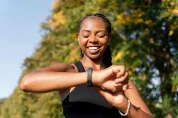 Smiling young woman checking time after jogging - obrazy, fototapety, plakaty