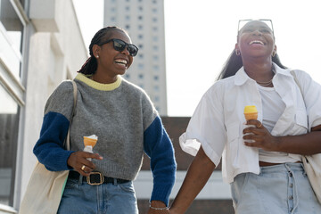 Young female couple walking in city and eating ice cream