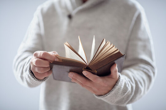 Man holding reading open holy bible or book with gray background