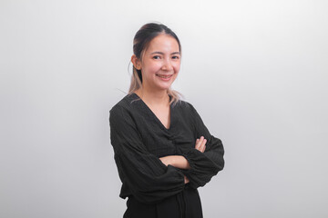 Portrait of Asian businesswoman in black casual wear cross her arm and looking at camera on grey background. Success and positive girl professional manager smile and happy about her work job.