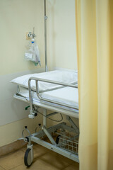 Hospital bed or stretcher with light yellow curtain and purified oxygen behind