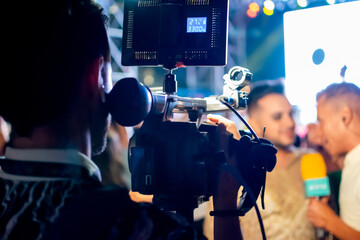 Camera man recording television reporter during interview at live event at night