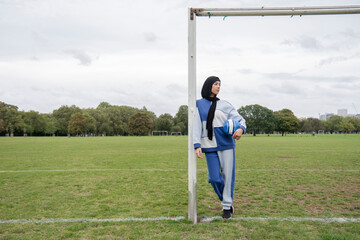 Obraz premium Portrait of woman in hijab standing in soccer field with soccer ball