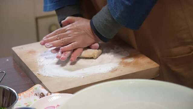 自宅でそばを打つ女性