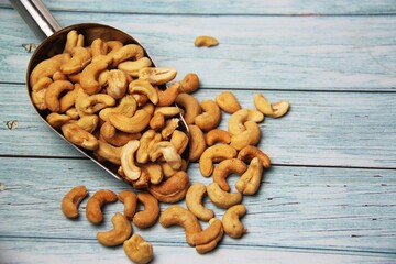 Close-up of roasted cashew nuts (Anacardium occidentale) on wooden table, space for text.Top view. Native of Brazil. Rich in magnesium, iron, zinc, selenium, vitamin A, E and antioxidants.