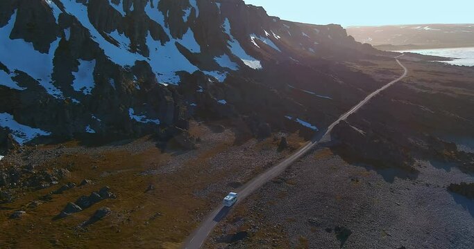 Aerial view of coast road 8100 to Hamningberg with with RV (recreational vehicle) moving along the road in sunny summer weather, Varanger Peninsula, Norway.