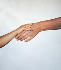 Young child holding their mother's hand against a white background.