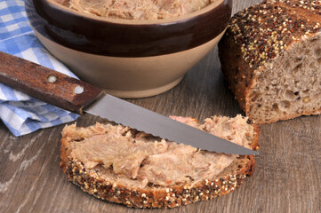 Tranche de pain aux graines avec des rillettes et un couteau en gros plan.