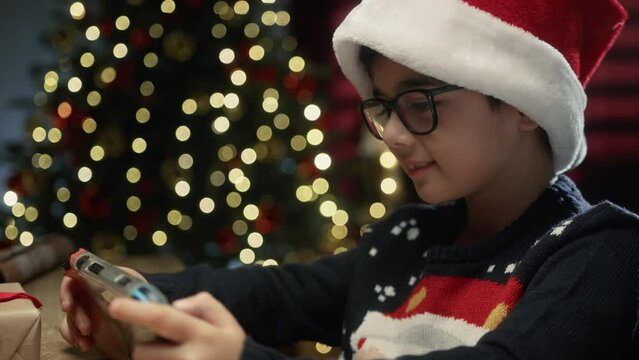 Child enjoying his Christmas gift videogame under the tree 