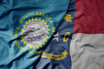 big waving colorful national flag of north carolina state and flag of south dakota state .