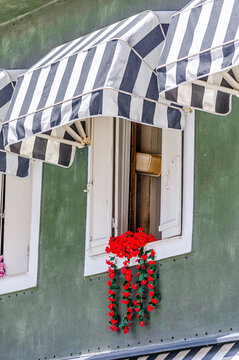 Charming Red Flower Hanging From Old Windowsill in a Rustic Style Building in Parga Town, Greece. Typical and Traditional Scene in Western Greece.