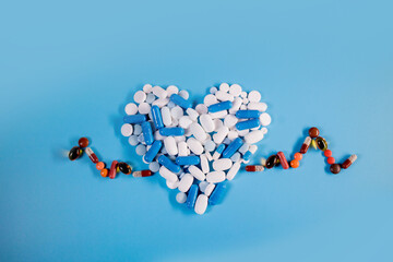 Heart shape from pills with cardiogram. Concept healthcare on blue background.
