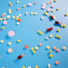 Colorful pills and capsules on blue background. Minimal medical concept. Flat lay, top view.