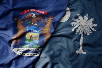 big waving colorful national flag of south carolina state and flag of michigan state .