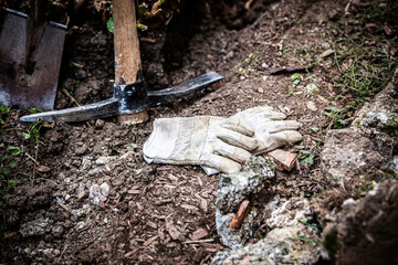 Obraz premium pickaxe and a spade in the garden, next to work gloves