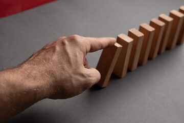 Domino has Fallen in a Row. Domino theory. Effect. Hand with Finger is Pointing and Pushing the Falling Wood Blocks. Risk Management, Revolution Concept. Affect Business. Closeup. Manifestation. Red