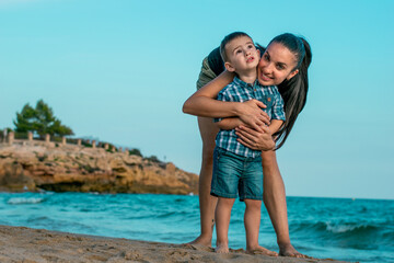 Fototapeta na wymiar Madre e hijo abrazados en la playa 