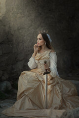 A beautiful red-haired girl in an old medieval dress with swords stands in the mountains and looks into the distance. Fairytale story about a princess. magic light. Warm artistic work. © olenakucher