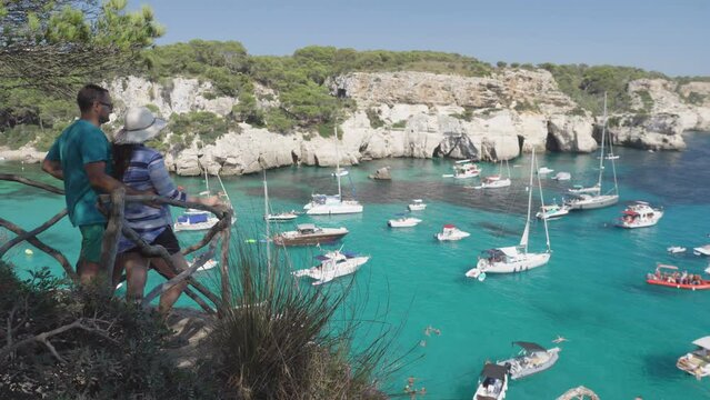 Tourists couple admiring panorama of Cala Macarella in Menorca Island Spain during summer holiday