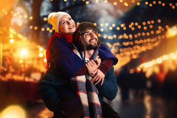 Happy couple smiling happiness standing and hugging outdoors on winter fair before Christmas. Spend...