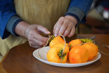 柿に紐を結ぶ女性