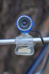 one black blue small web camera stands on a gray metal rod on the street