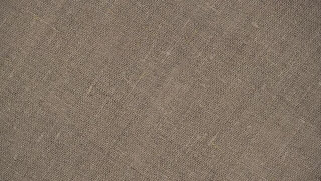 closeup rotation of durable burlap fabric. rough texture of natural fabric with a plain weave of threads. top view.