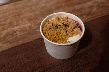 Ice cream blueberry cheesecake in white circle box on wooden table with selective focus.
