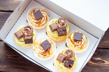 Salted caramel pistachio cupcakes with syrup, pretzels and bites of chocolate in gift box