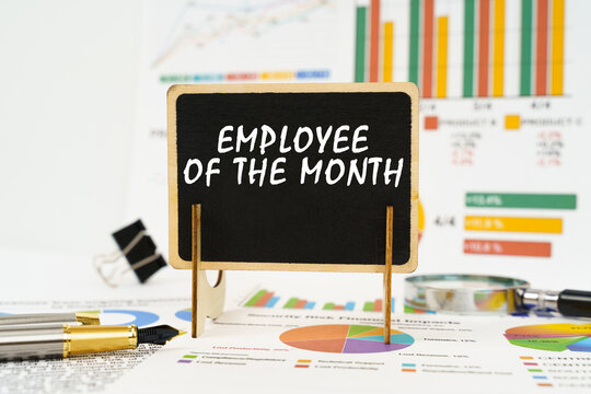 Against the background of business graphs, a board with the inscription - Employee of the Month