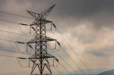 View of high electric voltage lines in cloudy weather. Electricity lines. 
