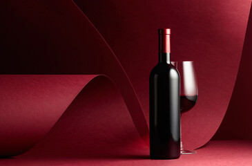 Bottle and glass of red wine on a red background. - Powered by Adobe