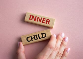 Inner Child symbol. Wooden blocks with words Inner Child. Beautiful pink background. Businessman hand. Business and Inner Child concept. Copy space.
