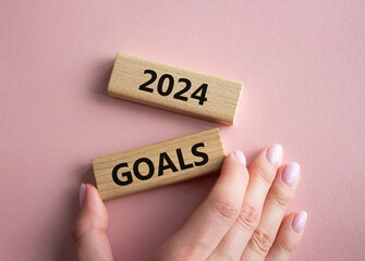 2024 Goals symbol. Wooden blocks with words 2024 Goals. Beautiful pink background. Businessman hand. Business and 2024 Goals concept. Copy space.