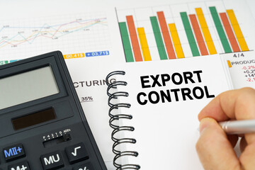 There is a calculator on the table, business charts, a man made a note in a notebook - export control
